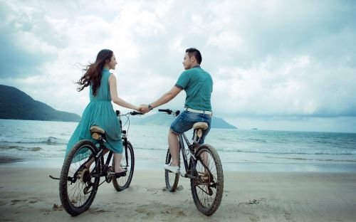 Casal de bicicleta na praia